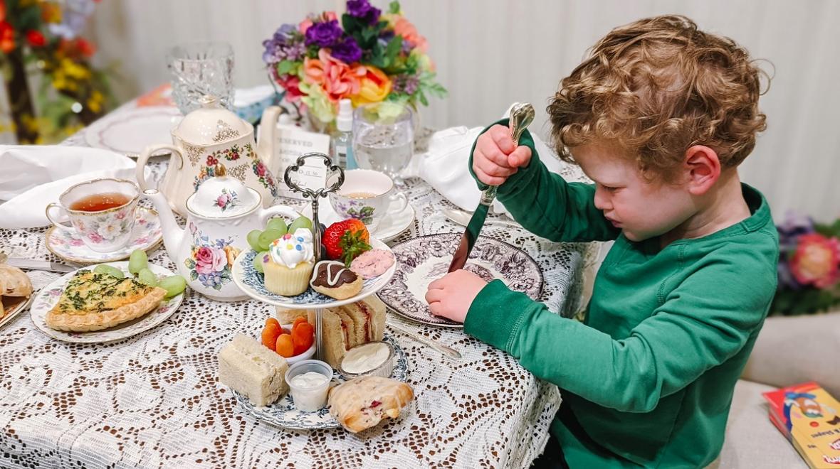 Young child having tea under flower decorations at Graham's Royal Tea