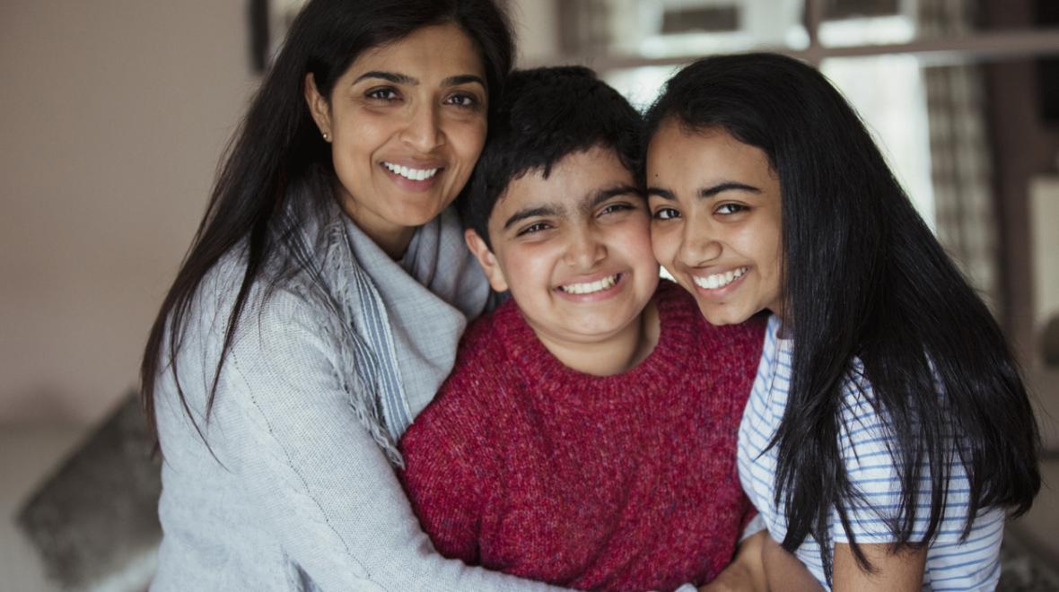 Boy hugged by sister and mother, all smiling