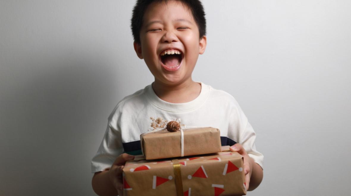 Young boy holding two packages with a big smile and eyes closed