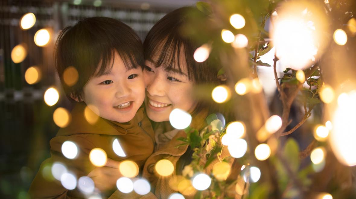 Mother and child's faces looking happily at holiday lights