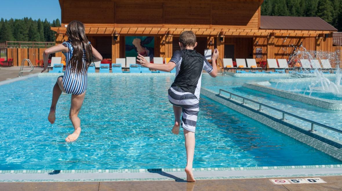 Two kids jump into the swimming pool at Suncadia Resort nearby vacation destination from Seattle to book now