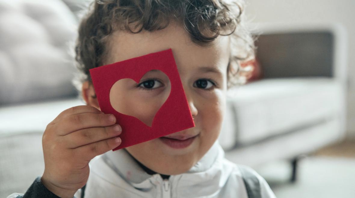 Young boy looking through a heart shaped cut out