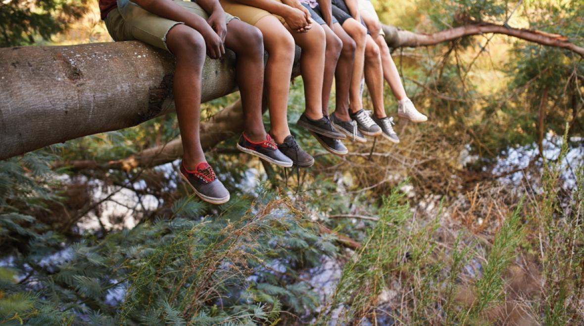 kids sitting on a log with feet dangling over edge