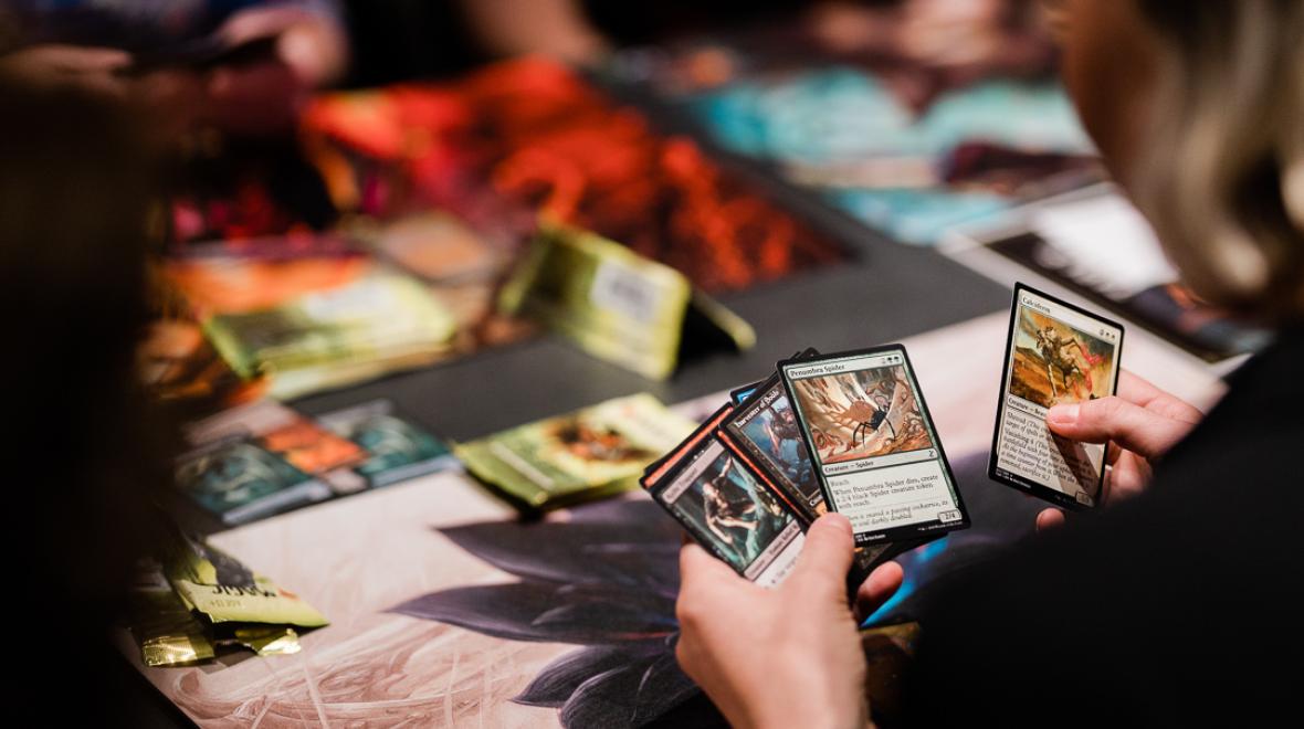 View of a table where a person (hands visible) is playing Magic the Gathering at Mox Boarding House, game cafe in Seattle and Bellevue