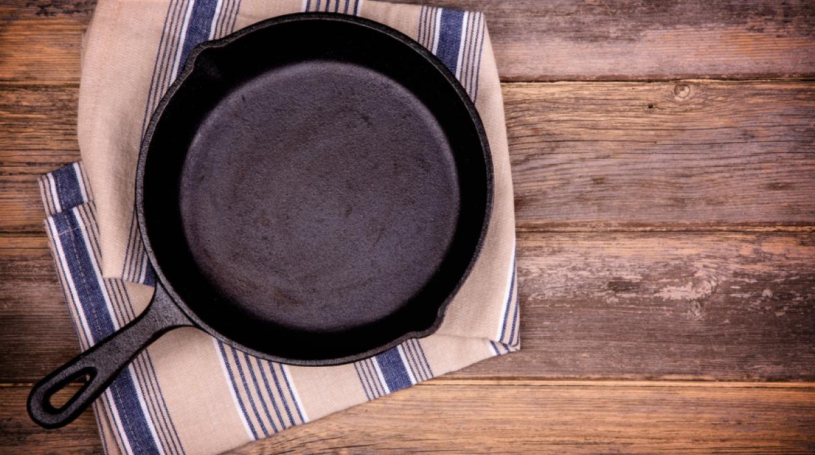 Cast iron skillet laying on a kitchen towel on a wooden countertop 
