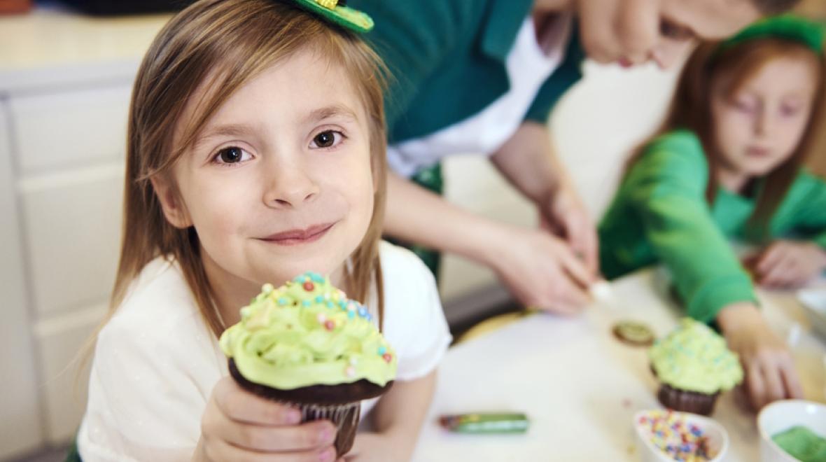 Young girl holding a cupcake with a St. Patrick's hat on