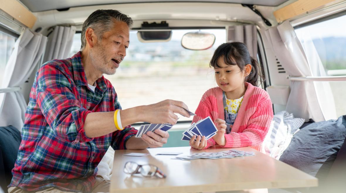 Dad and daughter sit in their camper van and play cards on a family road trip around Washington the family is from Seattle