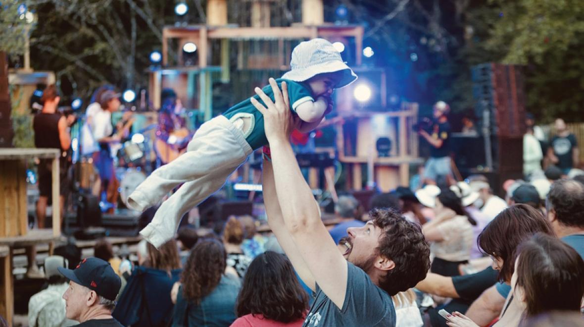 Man holding up baby at an outdoor Seattle music festival 