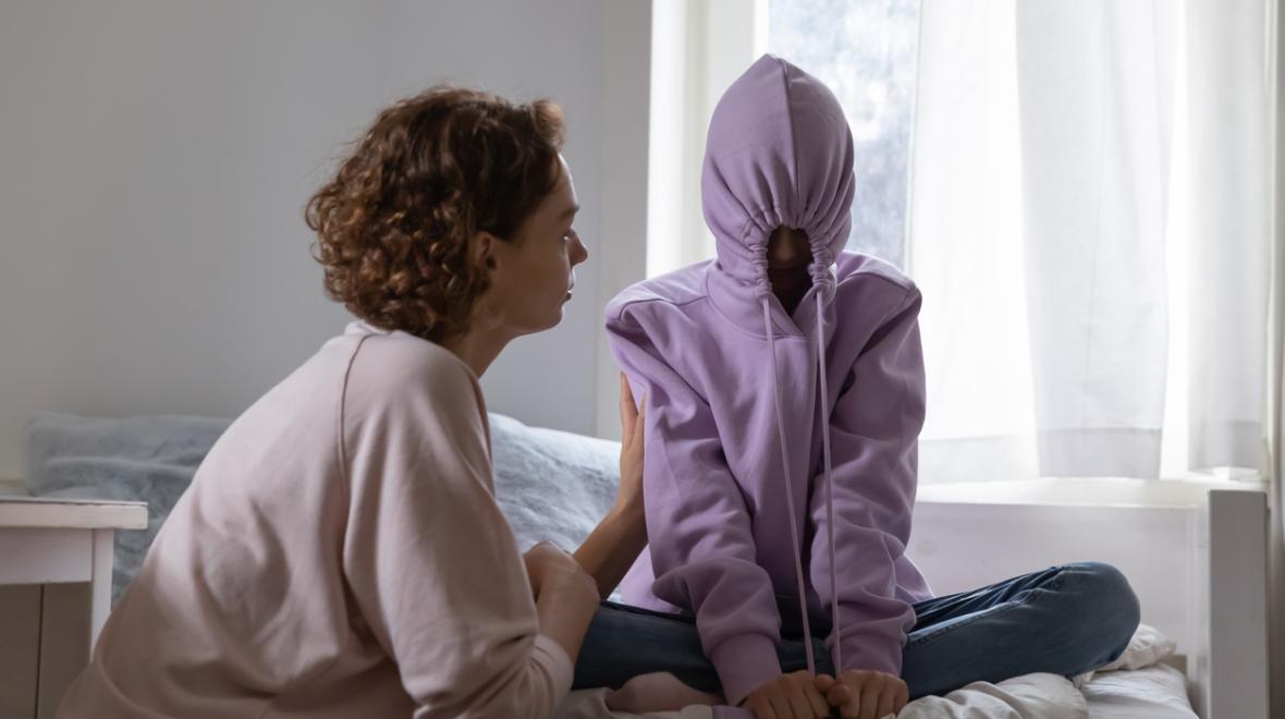 Stubborn teenage girl putting hood on avoiding talk with mom