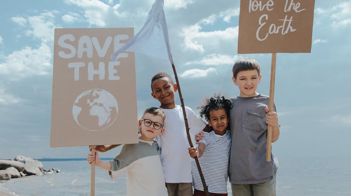 Three kids holding protest signs about protecting the environment