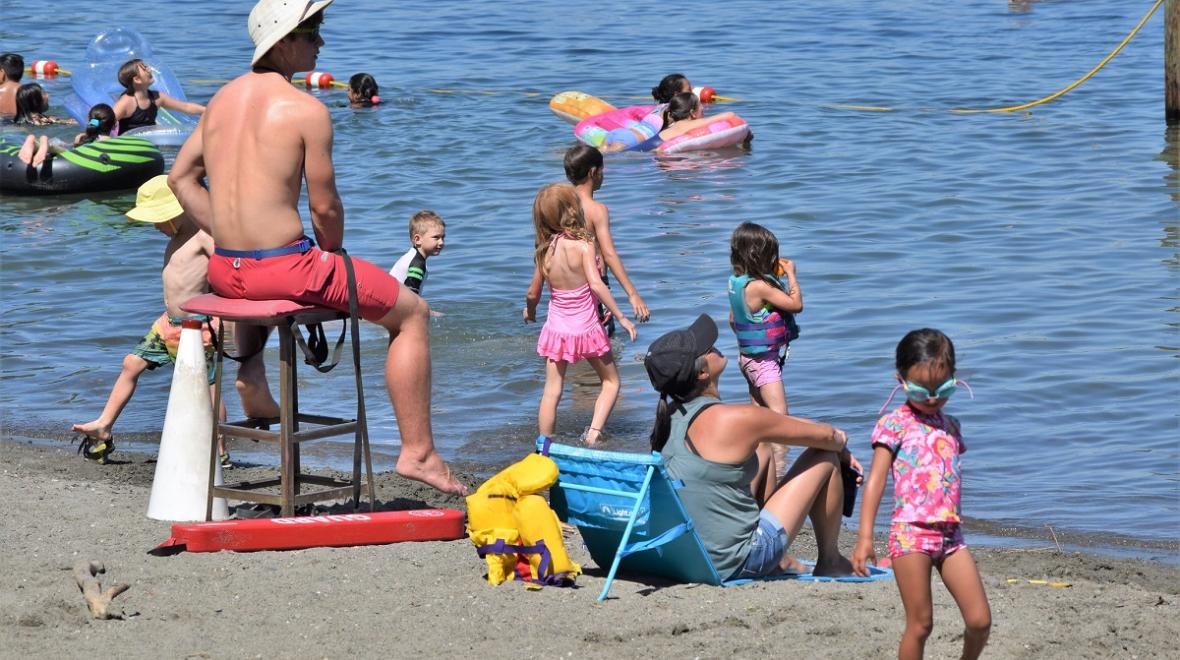 A lifeguard watches children swim at Seattle swimming beach where to swim in Seattle Mount Baker Beach on Lake Washington