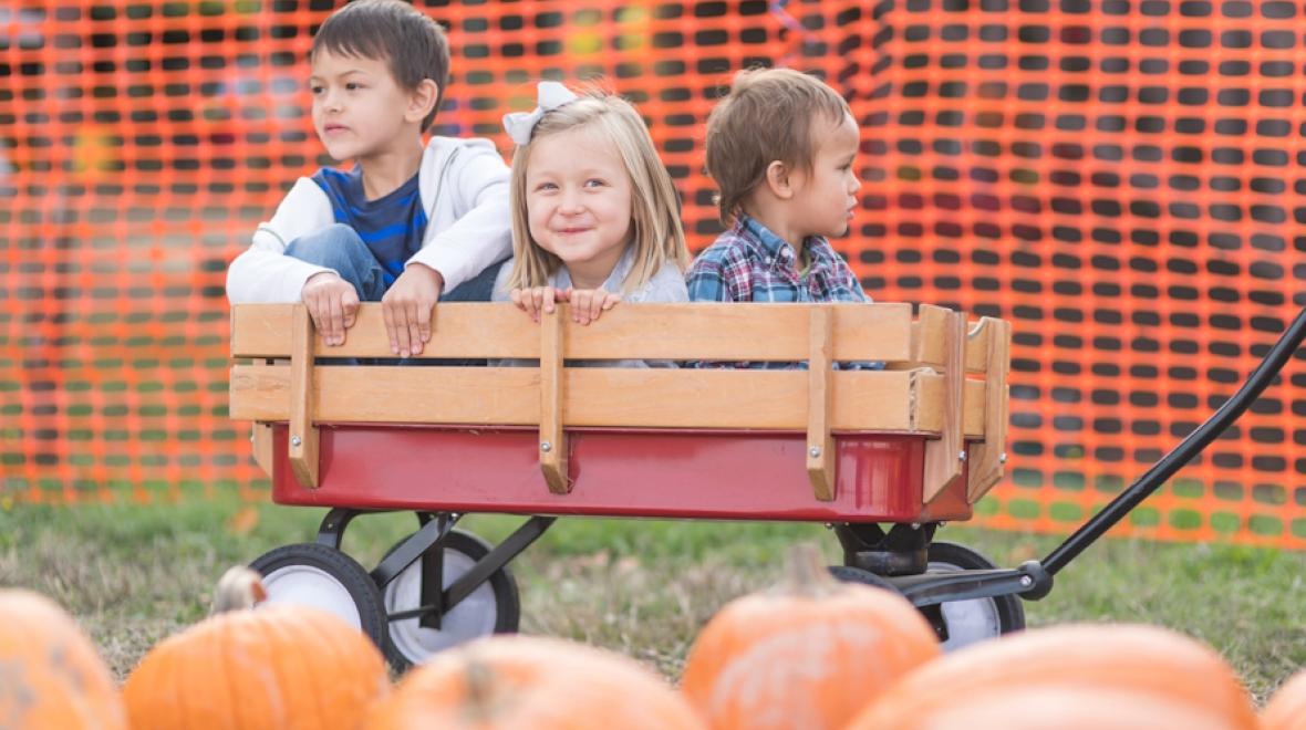 Three kids in a wagon at a pumpkin patch