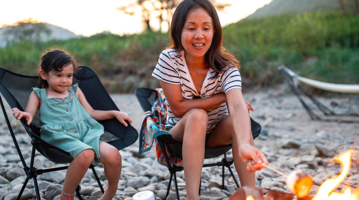 A mom and daughter play fun campfire games while camping and roasting marshmallows