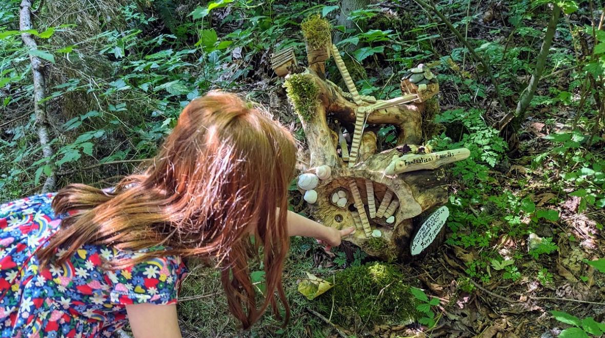 At the Sammamish Fairy House Trail by Beaver Lake, a girl points to a fairy home