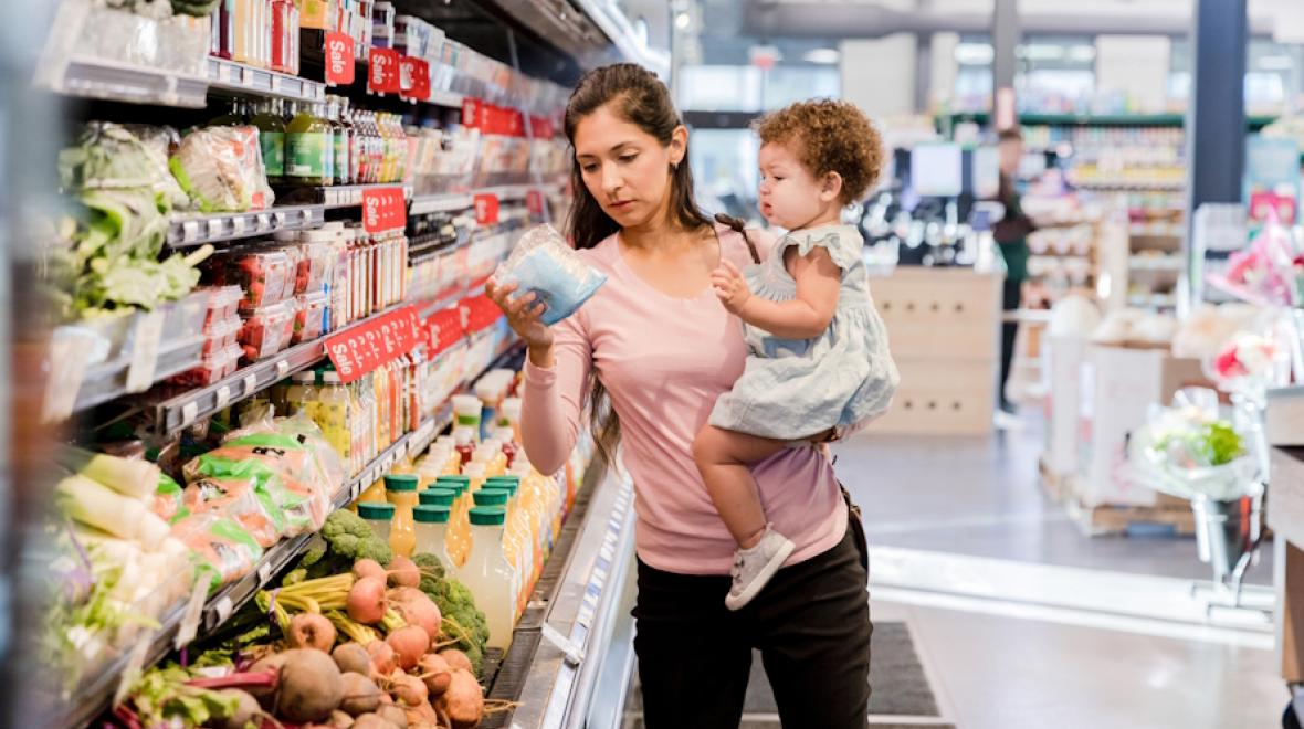 Mom shopping for food holding child