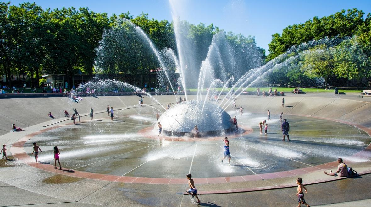 Kids play in the streams of water from Seattle Center's International Fountain on a fun summer day in Seattle