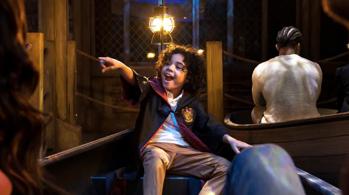 Young boy dressed in Hogwarts uniform enjoying the "Harry Potter: Magic at Play" exhibit