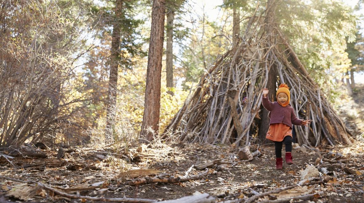 A young girl plays in the woods on a Seattle nature adventure, building a fort with sticks and branches
