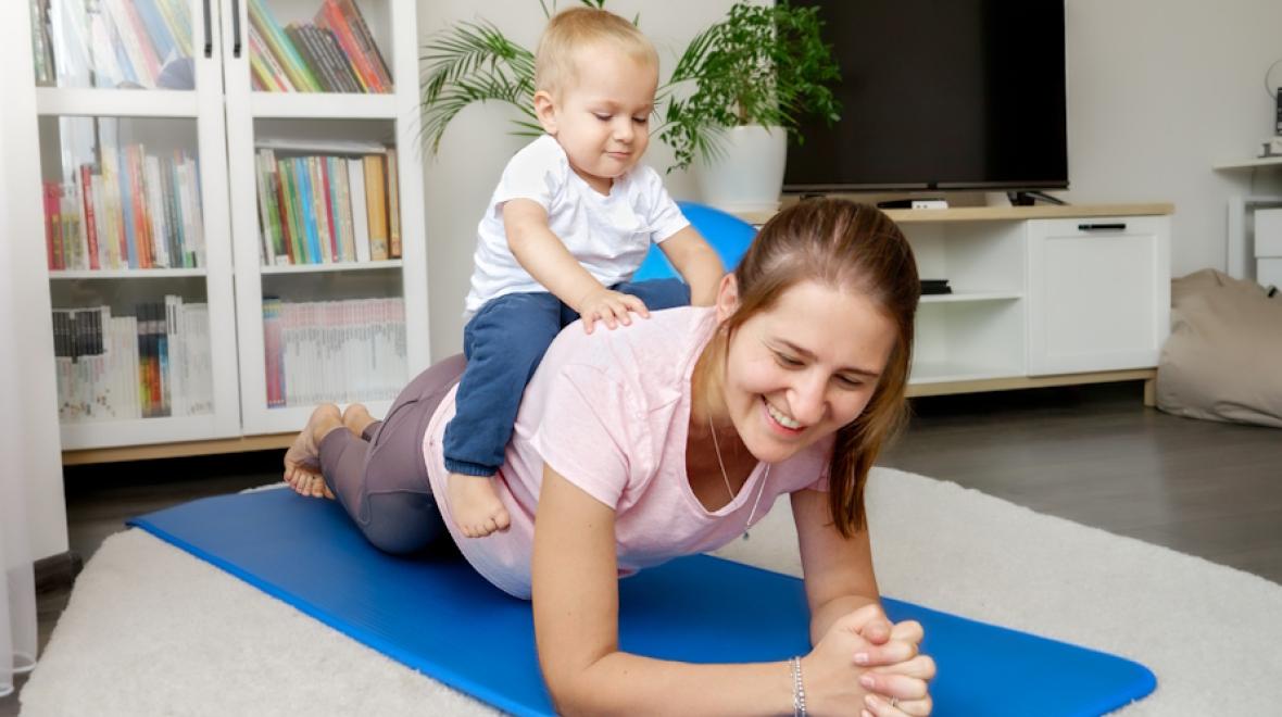 mom on a yoga mat with a baby on her back