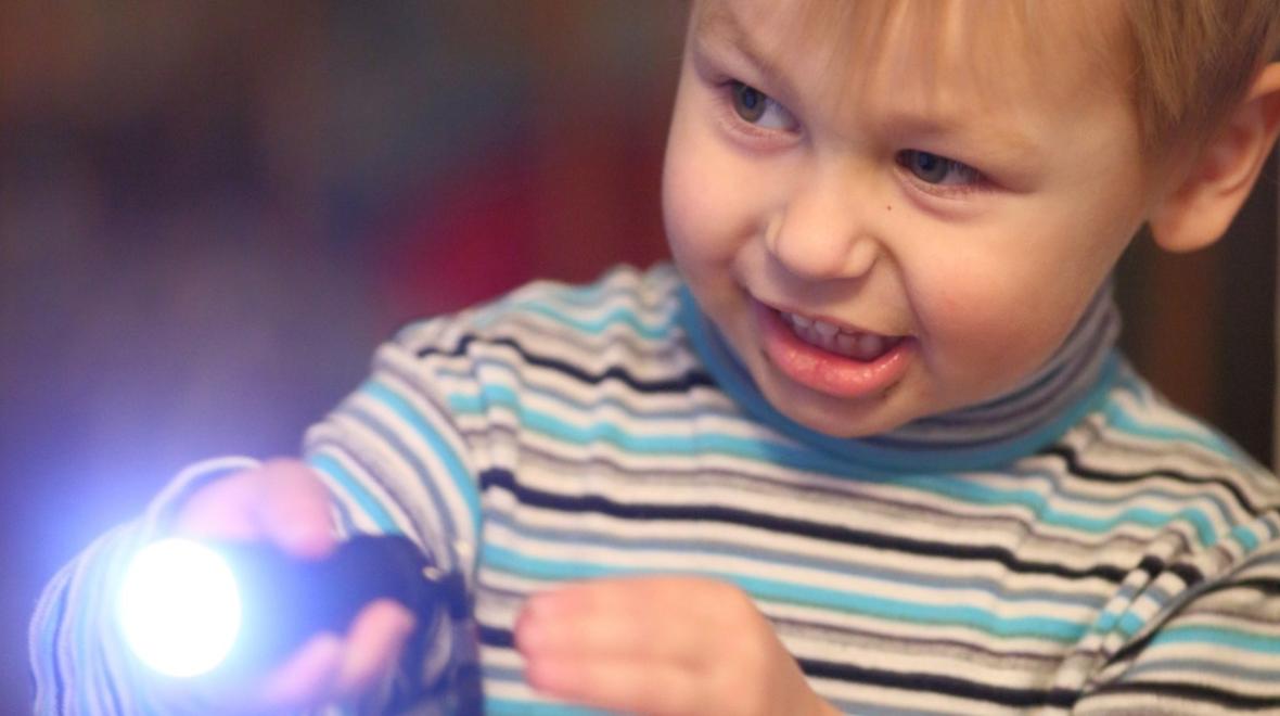 A boy with a flashlight gets ready to play outside after dark clever games with head lamps, glow in the dark paint and more