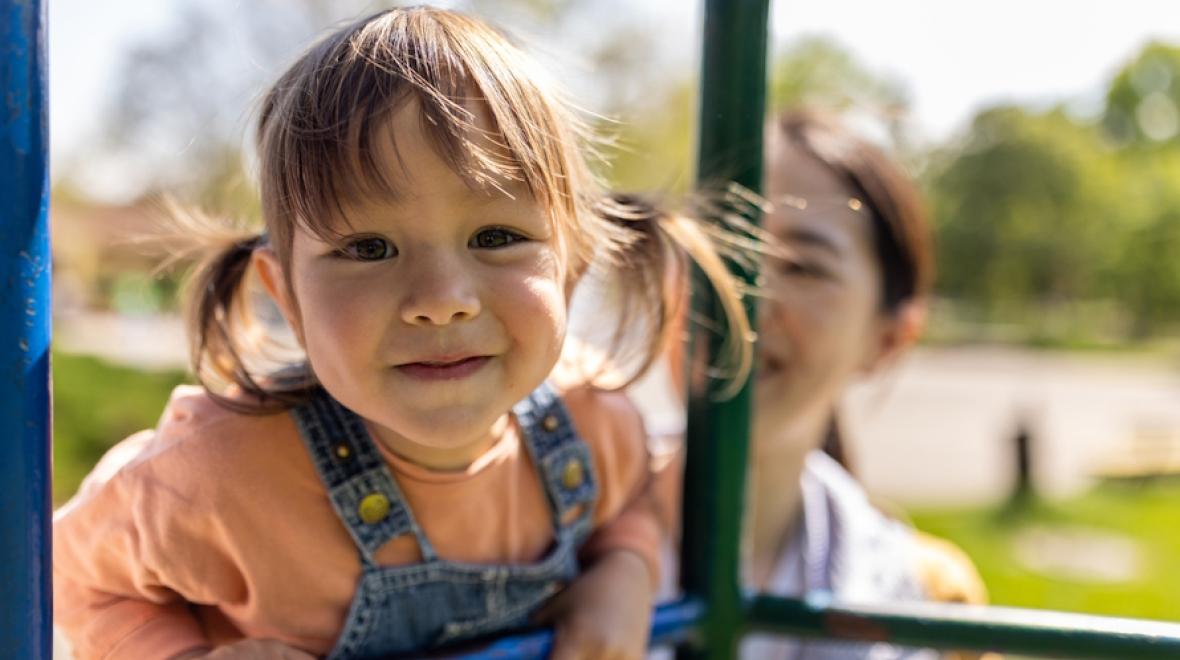 Little girl smiling and climbing on a play structure 