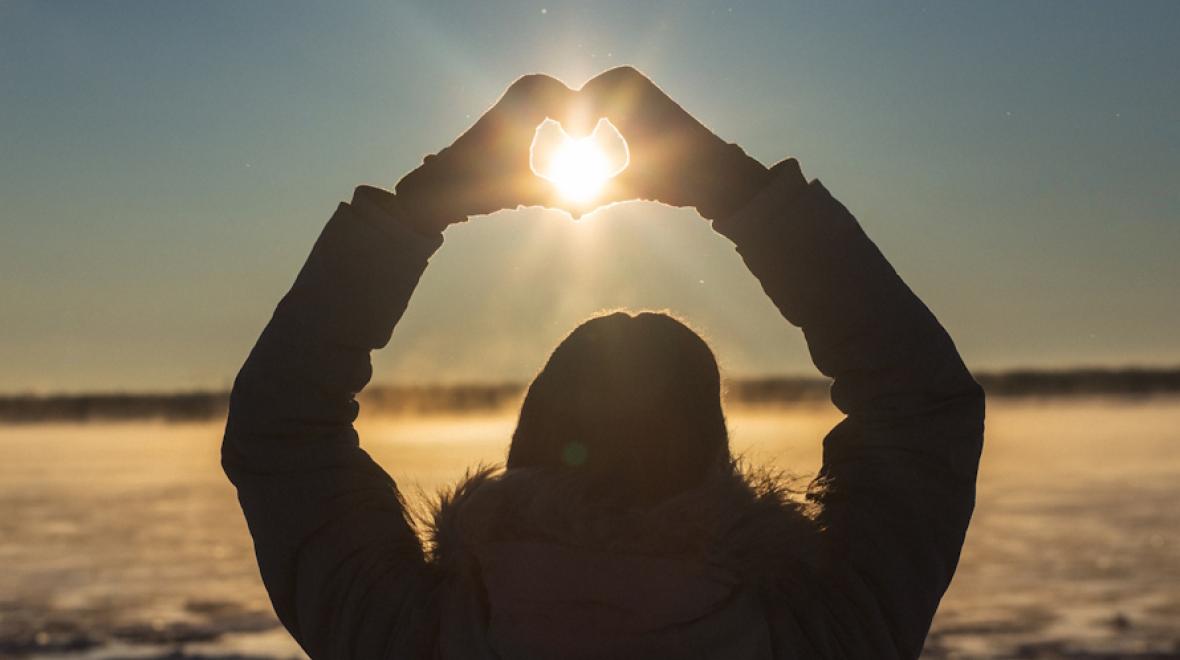 Hands made into a heart around the sun during the winter solstice
