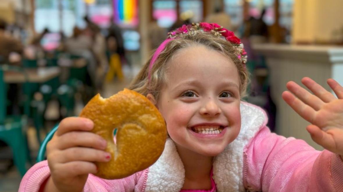 Young girl smiling and holding a bagel