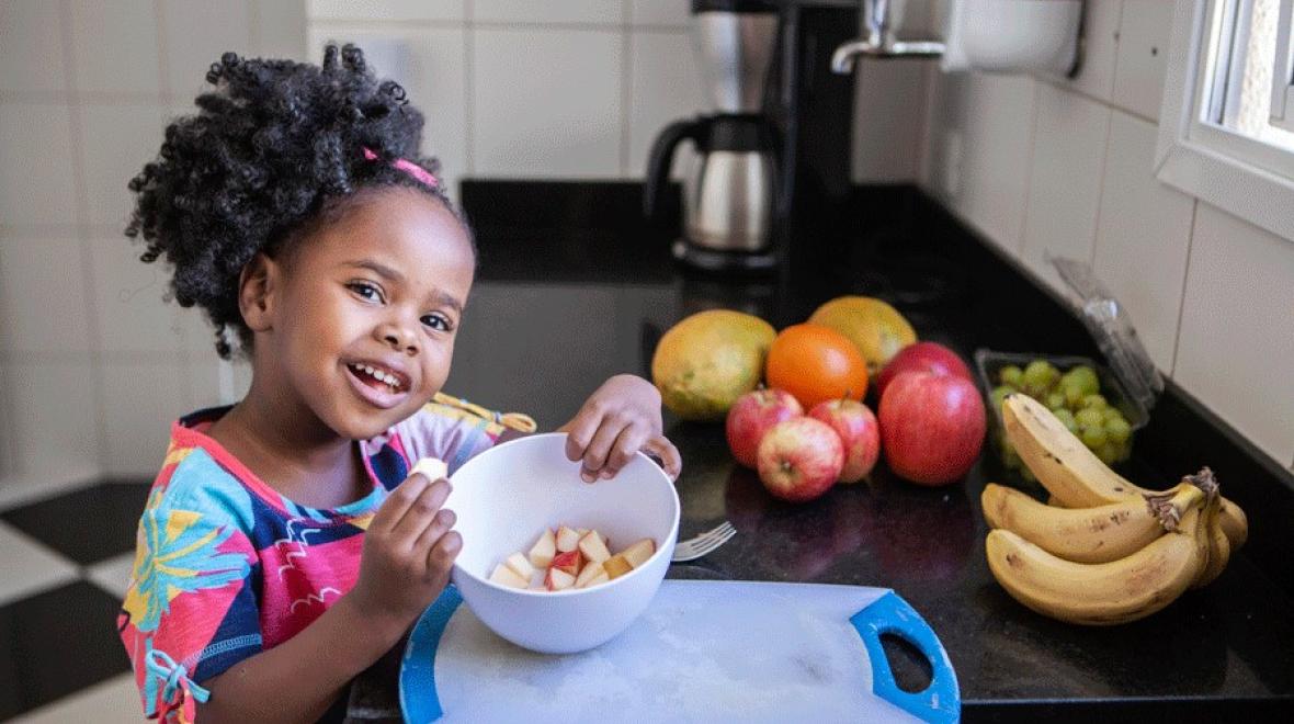 a young girl shows off cut apples in a bowl after using clever tool to motivate picky eaters