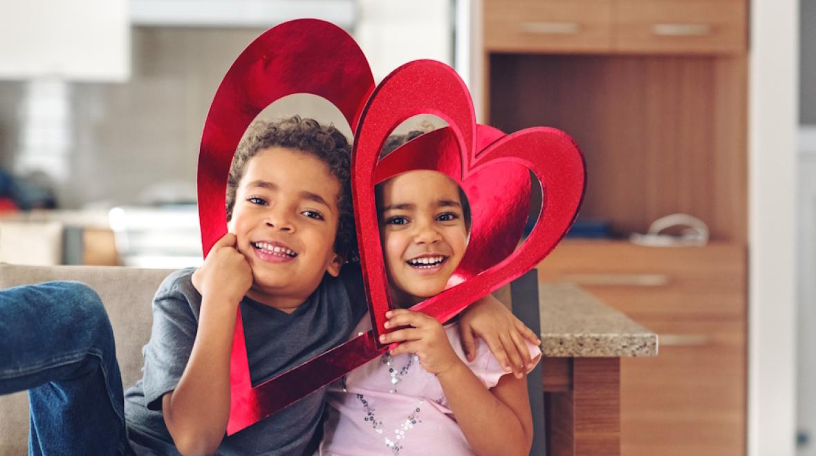 Two kids with paper hearts by their faces and useful Valentine's Day favors