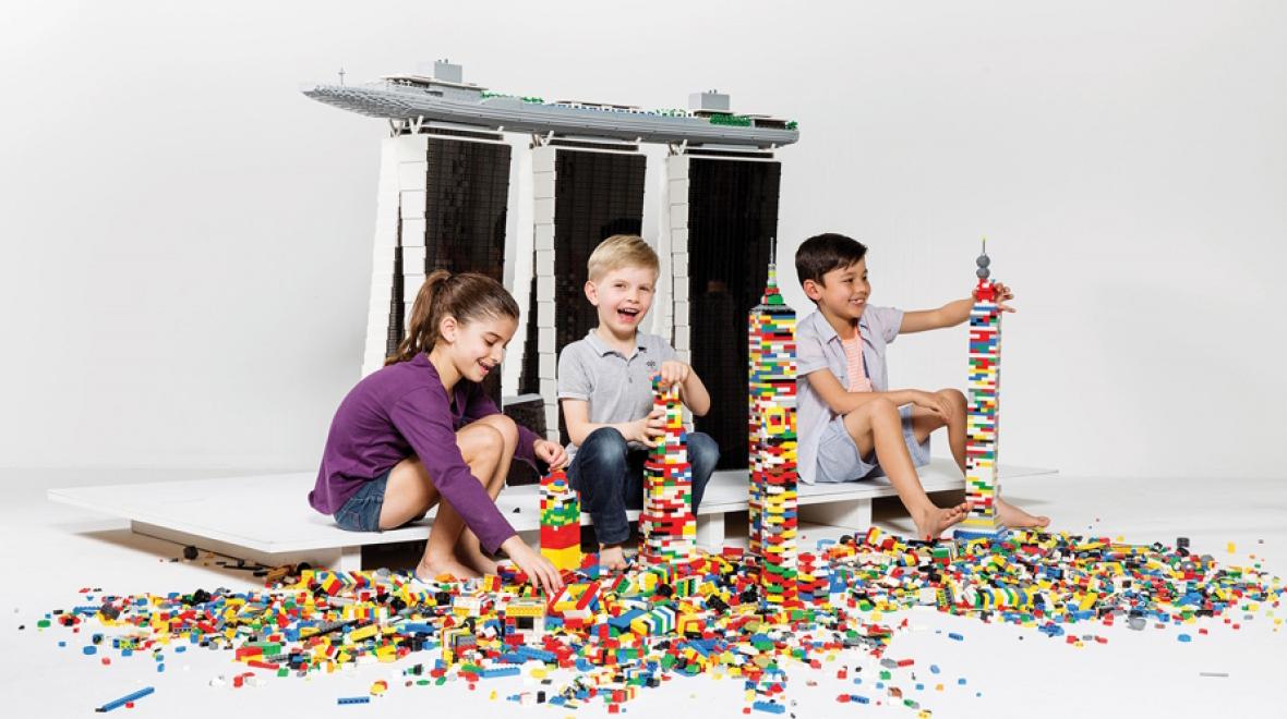 Three children building with lots of Legos