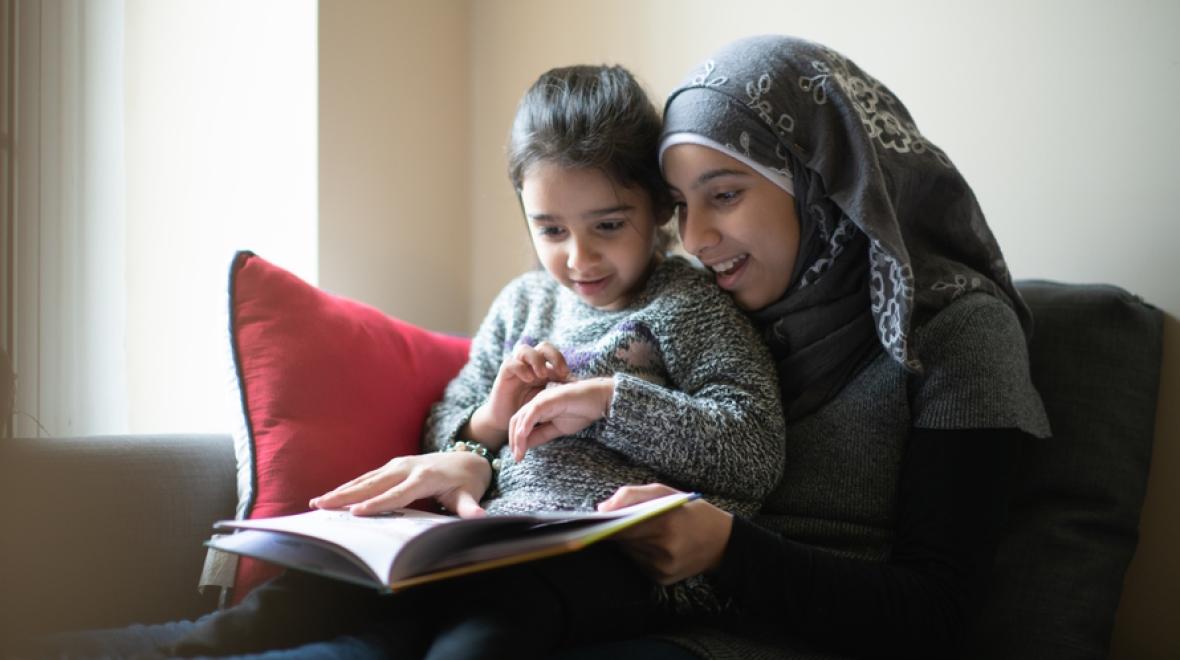 Two Muslim girls reading a book together