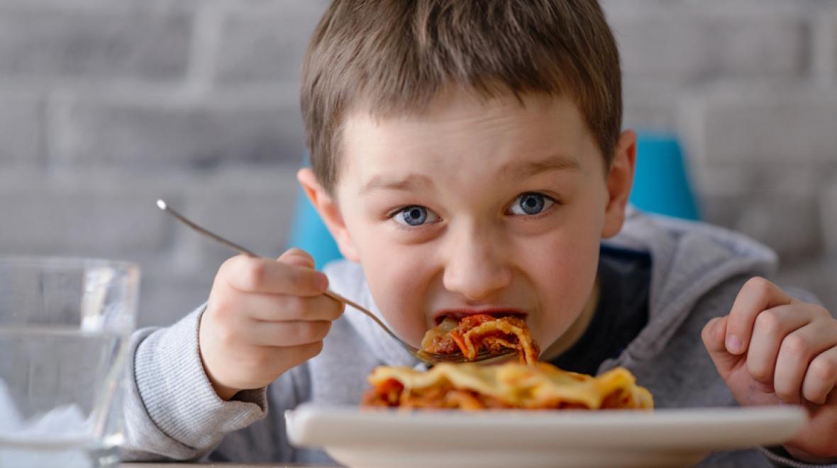 Boy eating frozen lasanga is a simple frozen meal for families