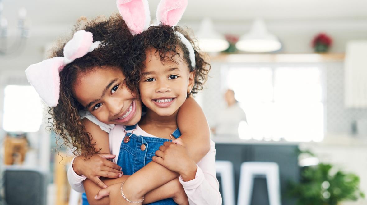 Cute sisters wearing bunny ears share a hug. Best Seattle Easter events for kids and families 2024