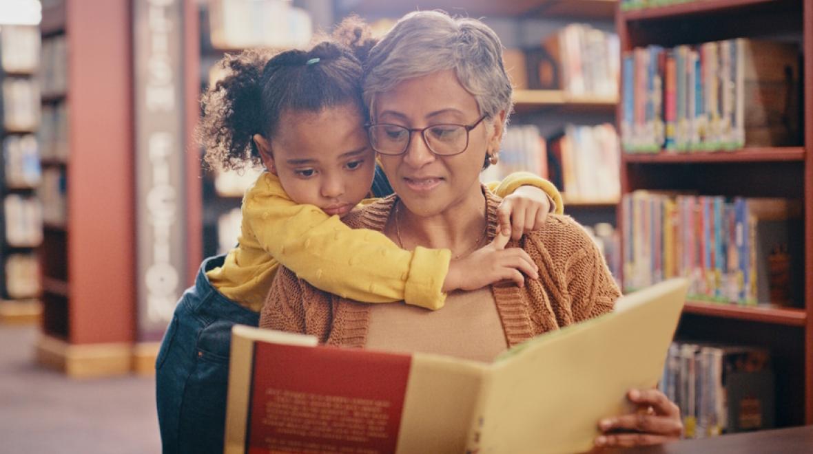 Mom and little girl reading a women's history month book at the library