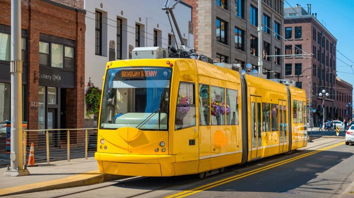 A bright yellow Seattle Streetcar heads through the city on a train adventure for families
