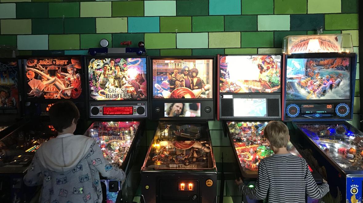 Two kids playing pinball machines at the Ice Box in Seattle