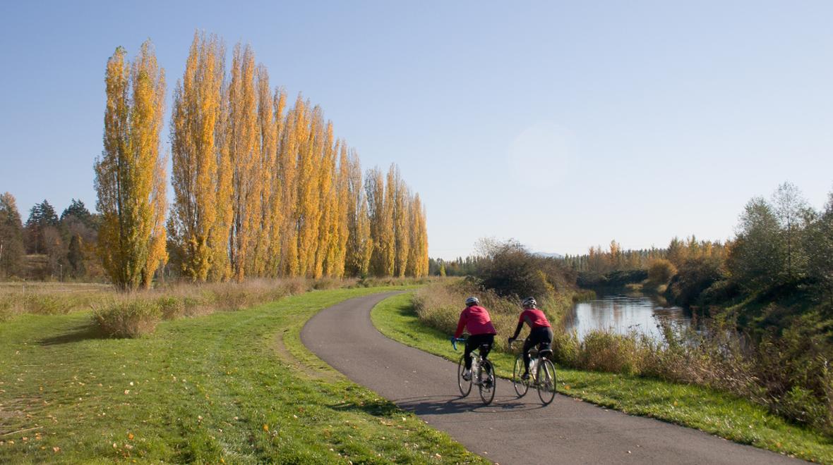 Two people on a bike ride on a kid-friendly hiking trail near Seattle along a river