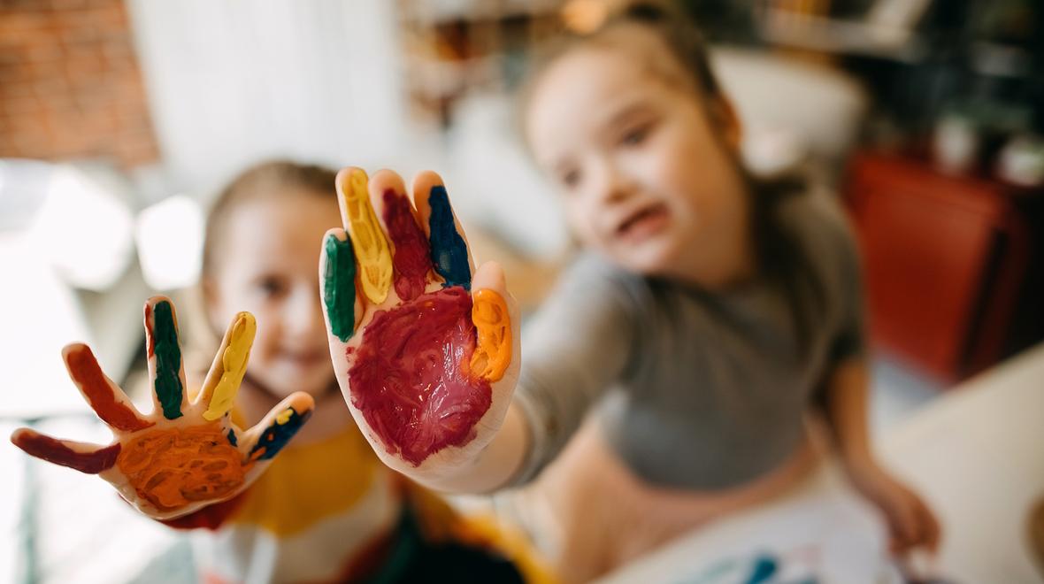 Kids with painted hands ready to make a handprint turkey, a Thanksgiving craft