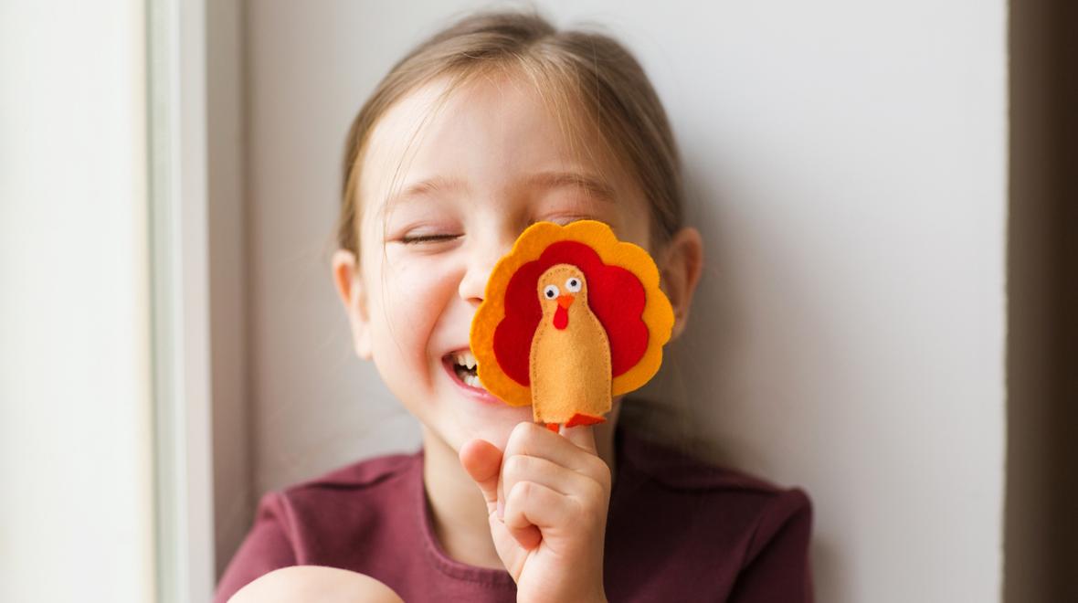 Girl with a felt turkey finger puppet she made as a Thanksgiving craft