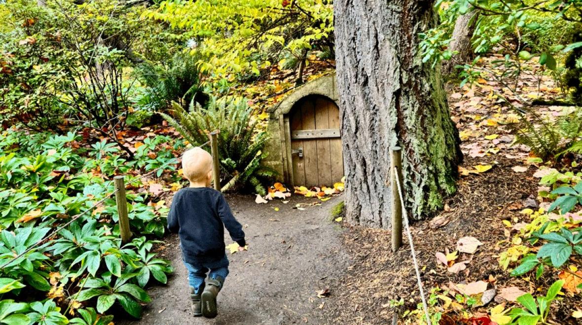 Young boy walking up to hobbit door at Bellevue Botanical Garden, a city nature walk for Eastside and Seattle families