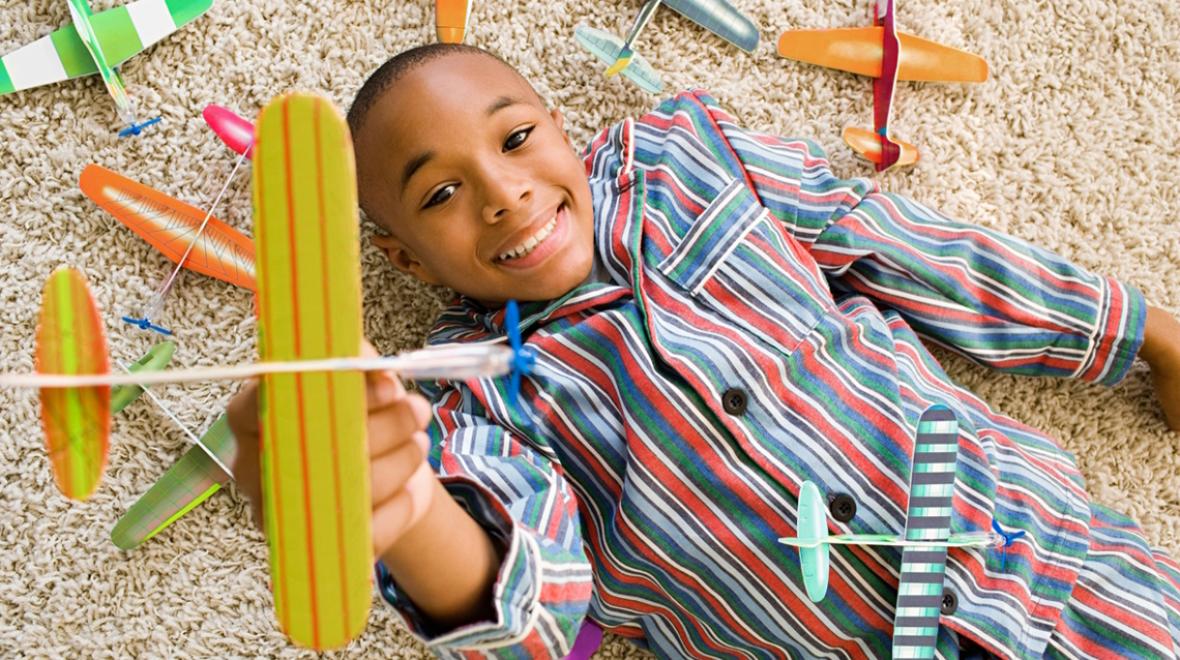 boy lying on the floor with toy airplanes