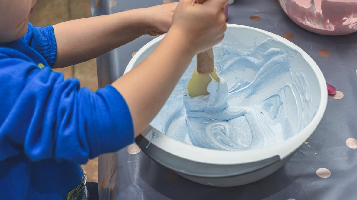 child mixing shaving cream and food coloring