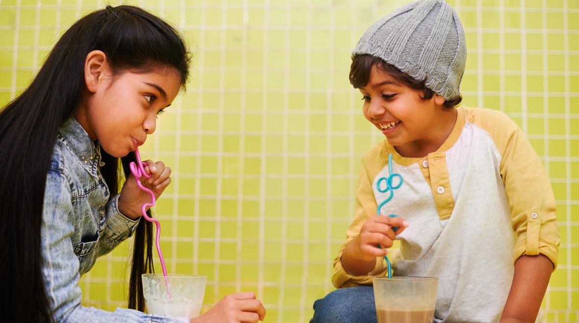 two kids drinking out of cups with crazy straws
