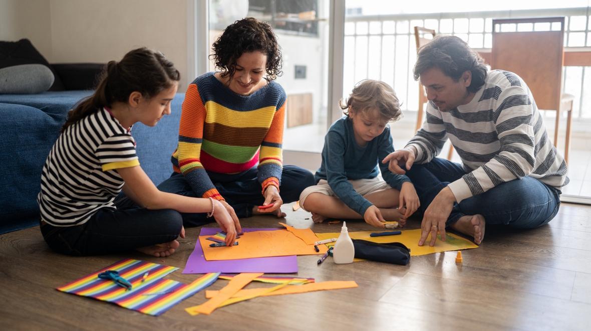 Family sitting on the floor making a craft together with rainbows