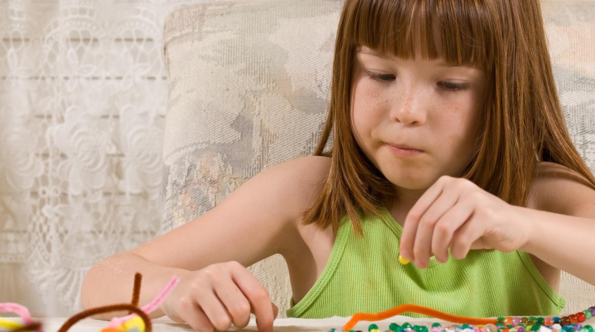 Young girl stringing beads onto a pipe cleaner