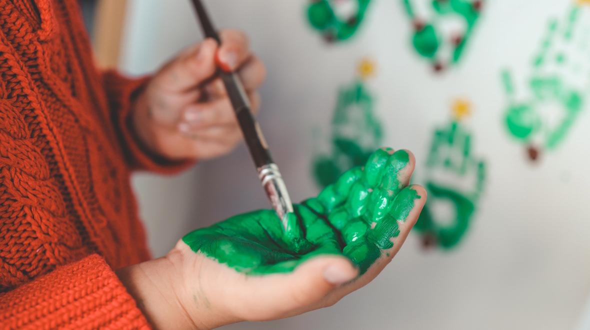 child painting their hand green to make a shamrock print