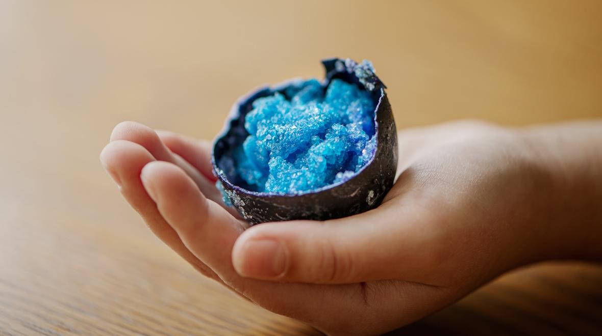 blue crystals in an eggshell held in a child's hand