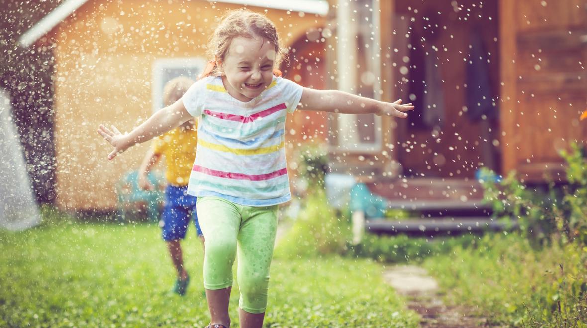 kids playing in a sprinkler outside summer