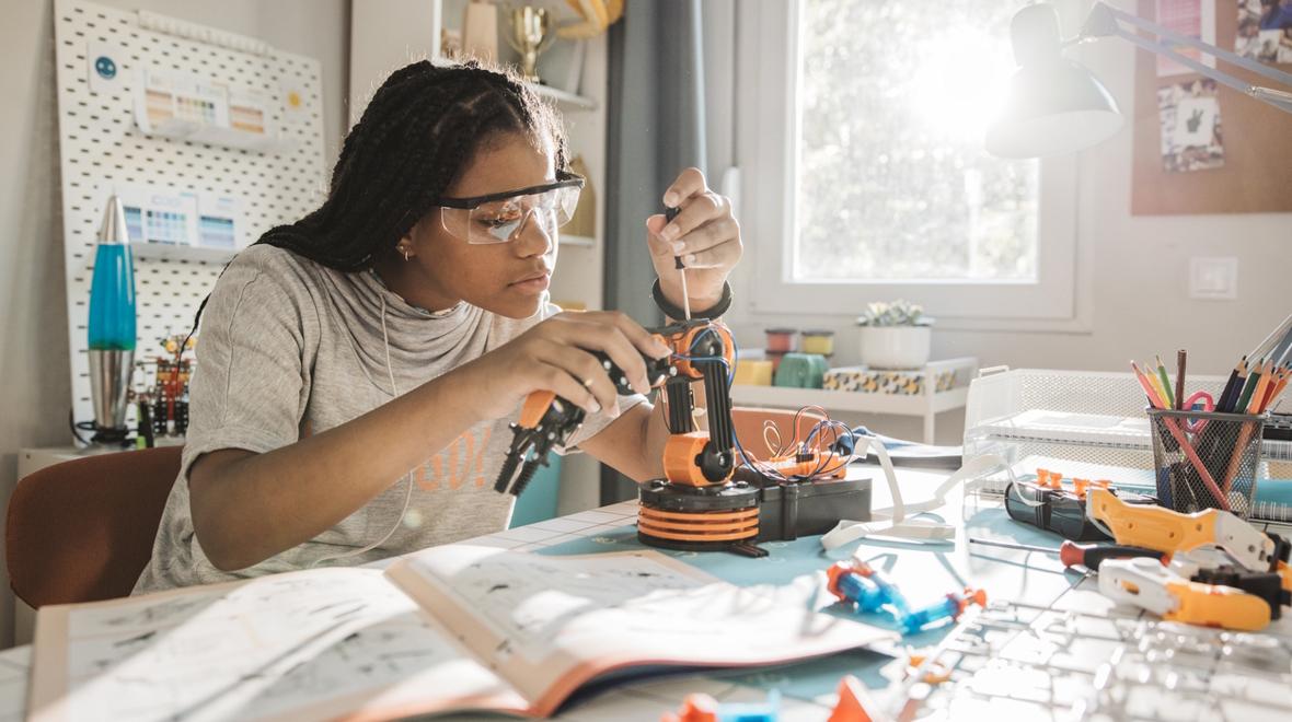 teen girl building a robotic arm at home for a summer activity