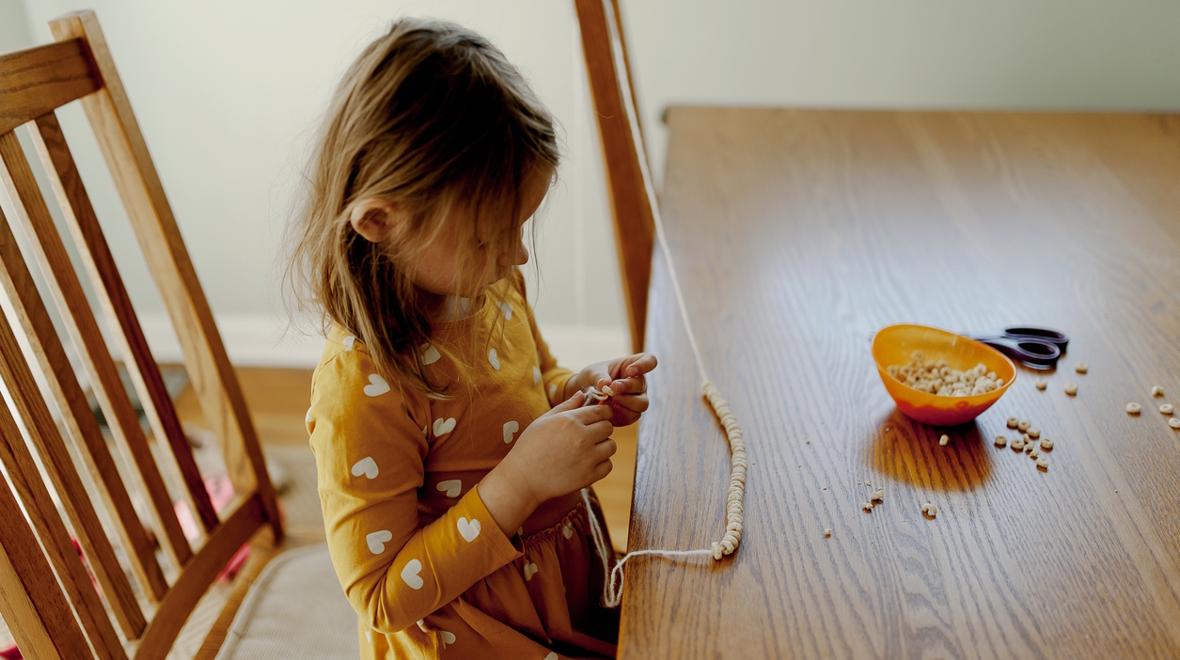 child making a necklace out of snack foods